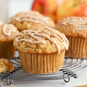 Apple cinnamon muffins on a wire rack topped with a cinnamon icing drizzle.