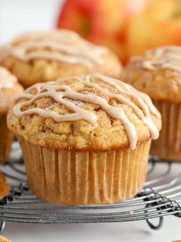 Apple cinnamon muffins on a wire rack topped with a cinnamon icing drizzle.