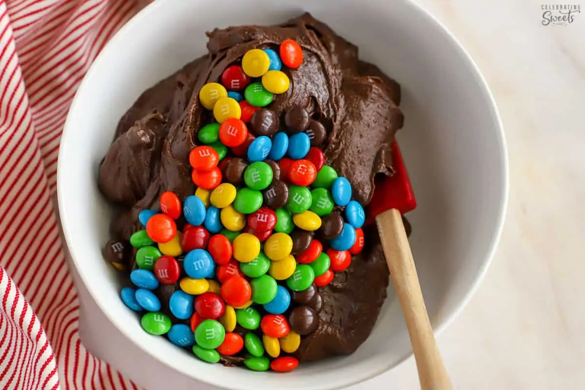 White bowl filled with brownie batter with M&M's on top.