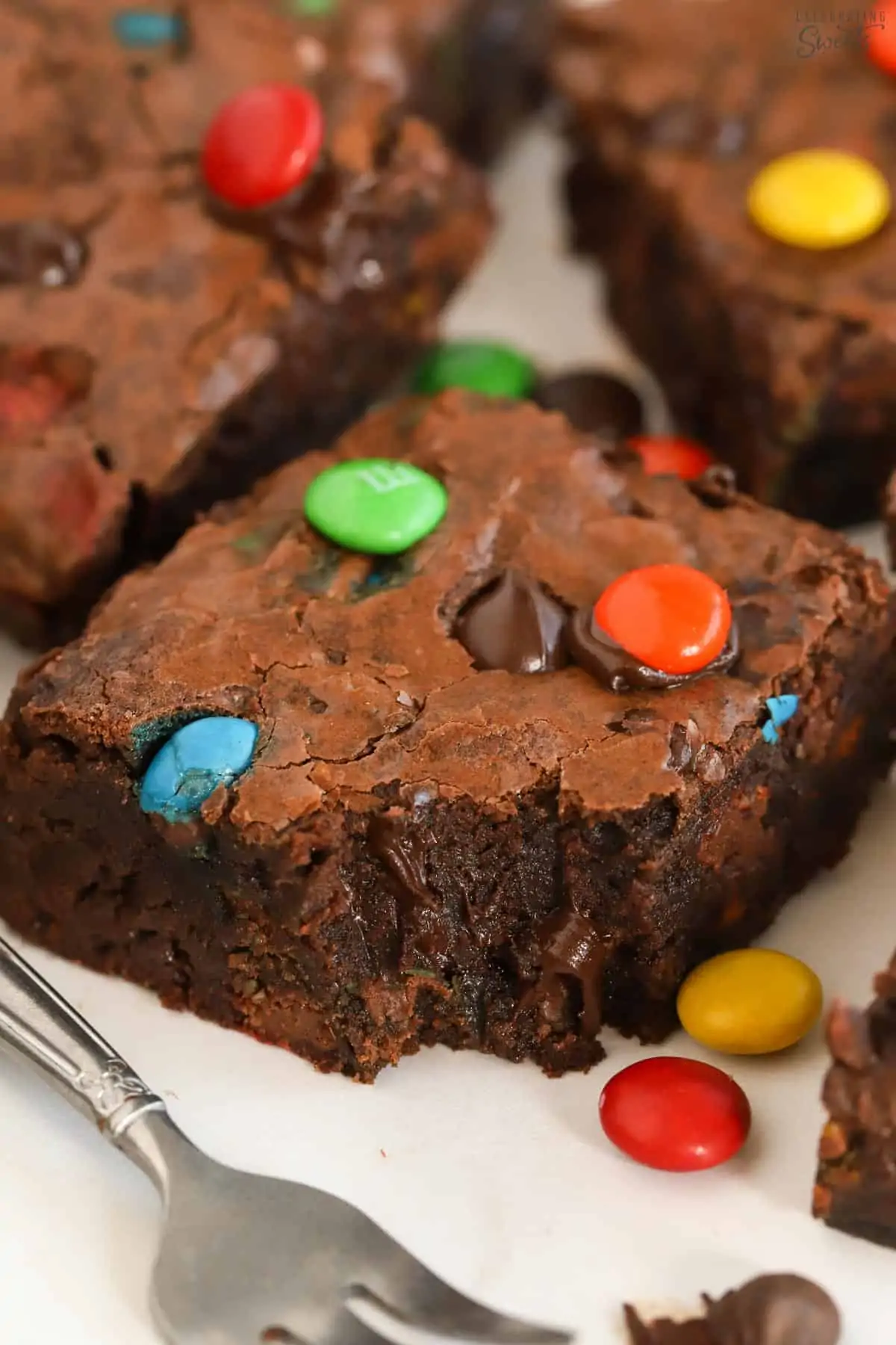 Closeup of an M&M Brownie next to a fork.