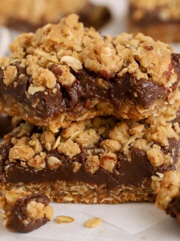 Two Oatmeal Fudge Bars stacked on a piece of parchment paper.