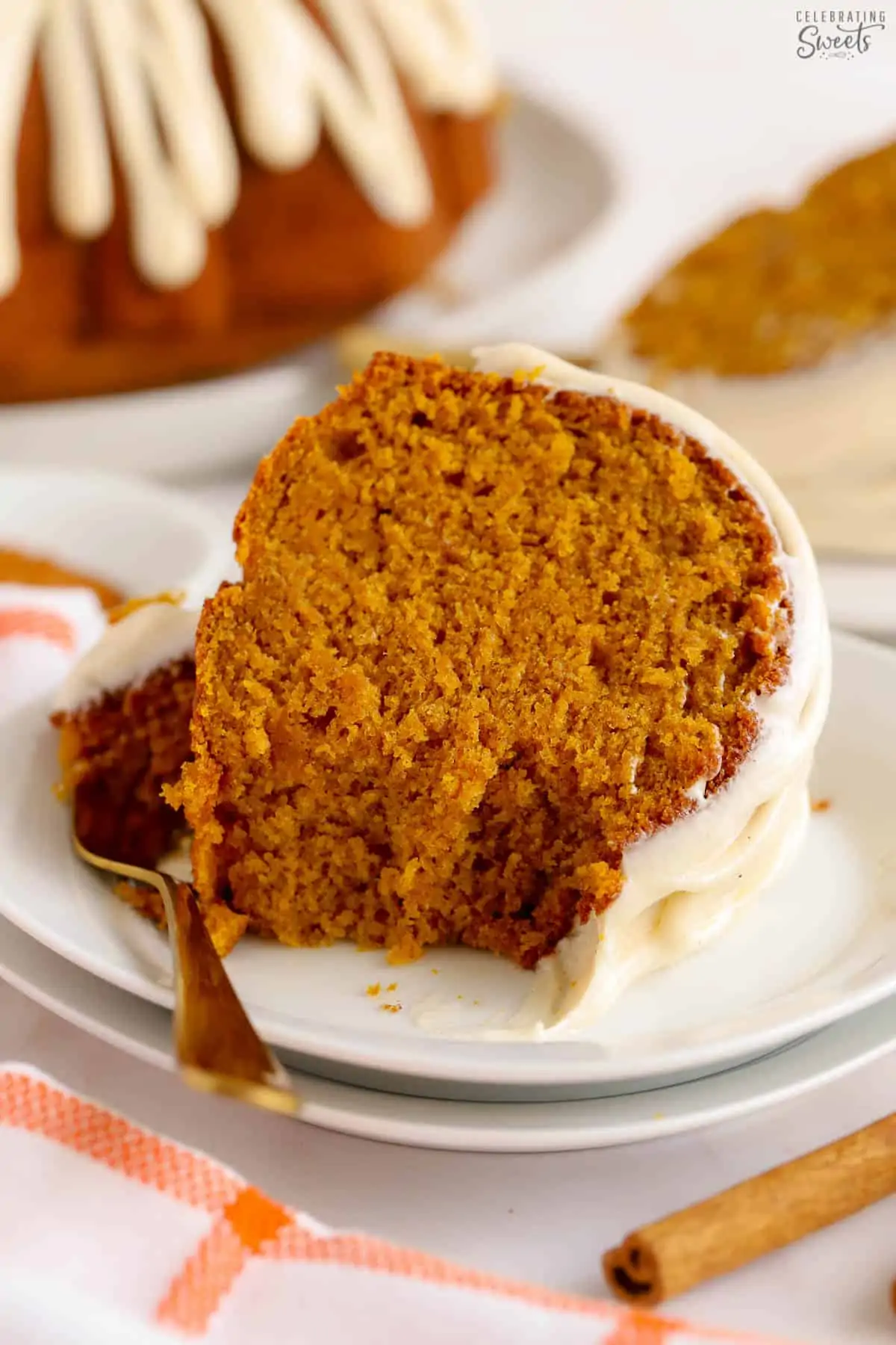 Slice of pumpkin bundt cake on a white plate with a gold fork.