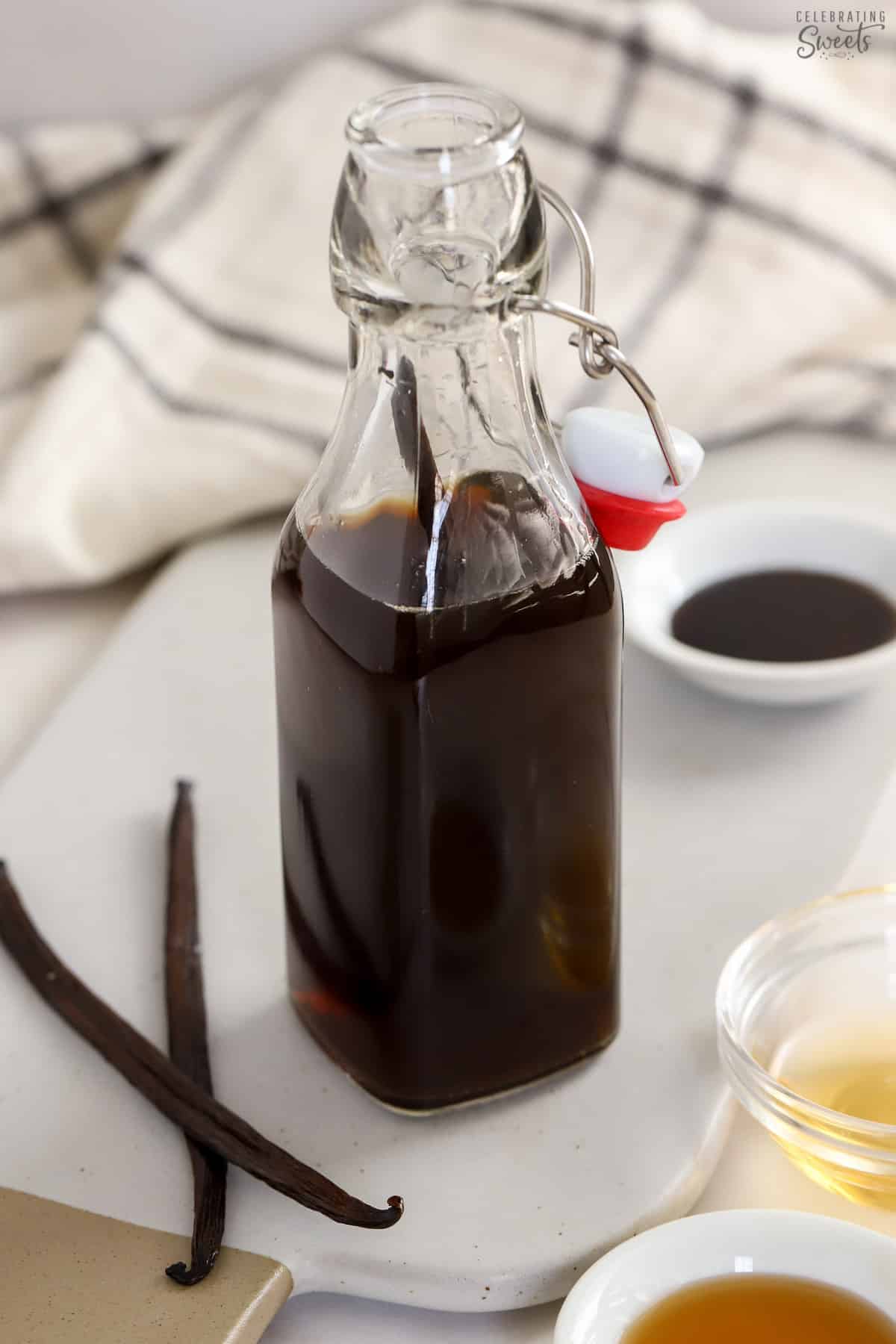 Vanilla extract in a glass container with vanilla beans next to it.