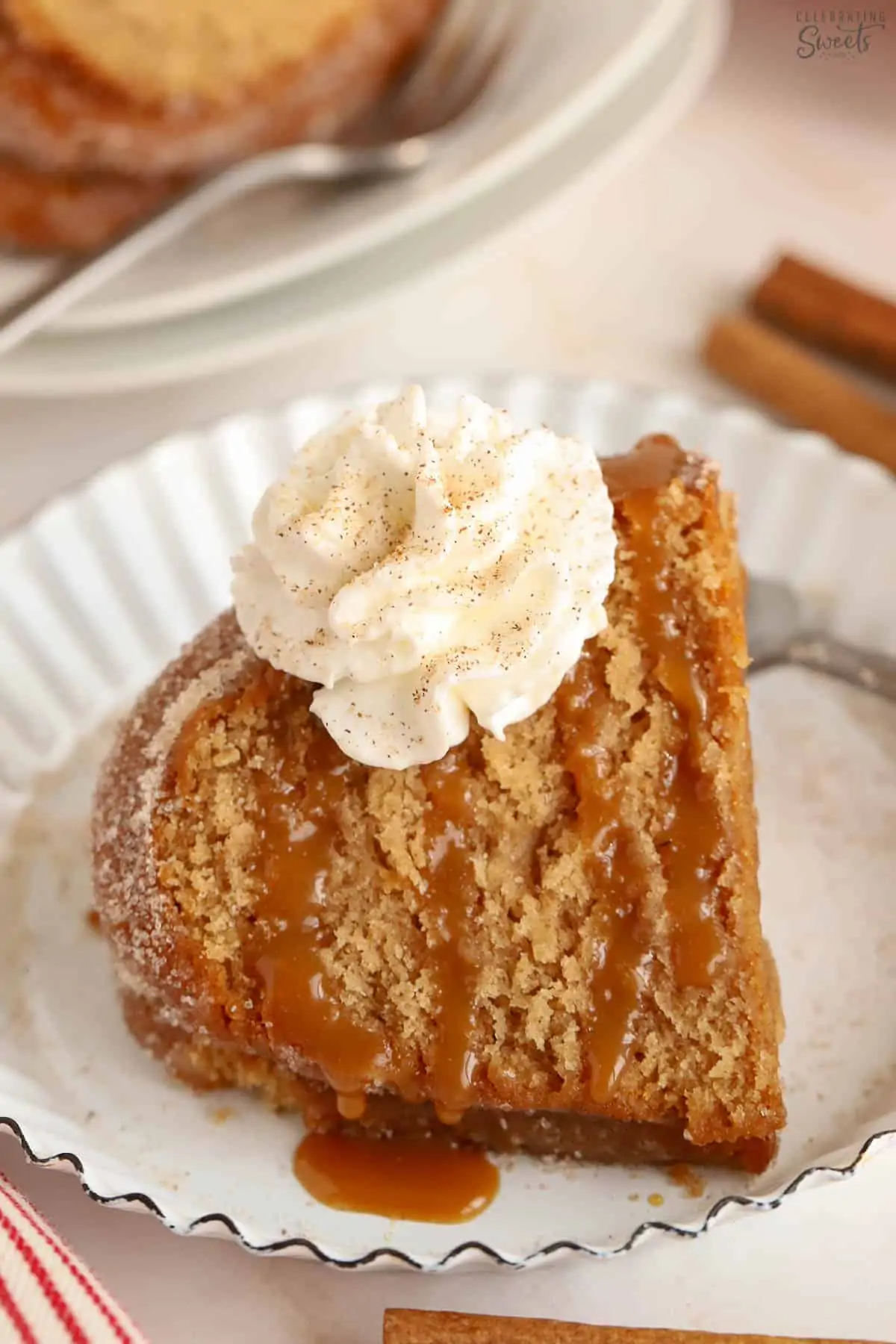 Slice of apple cider donut cake drizzled with caramel sauce and topped with whipped cream.