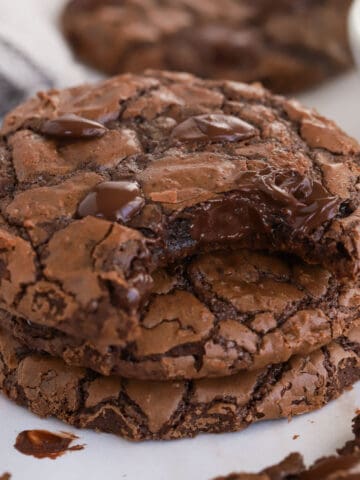 Stack of three brownie cookies with a bite taken out of the top cookie.