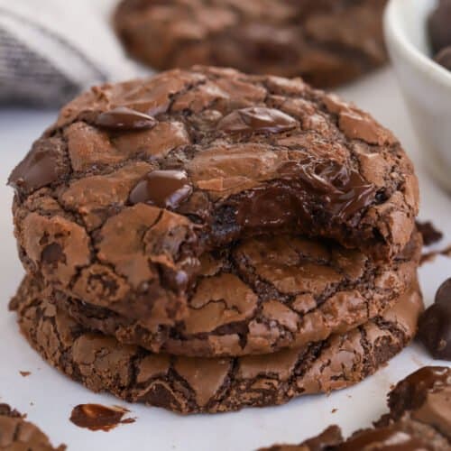 Stack of three brownie cookies with a bite taken out of the top cookie.