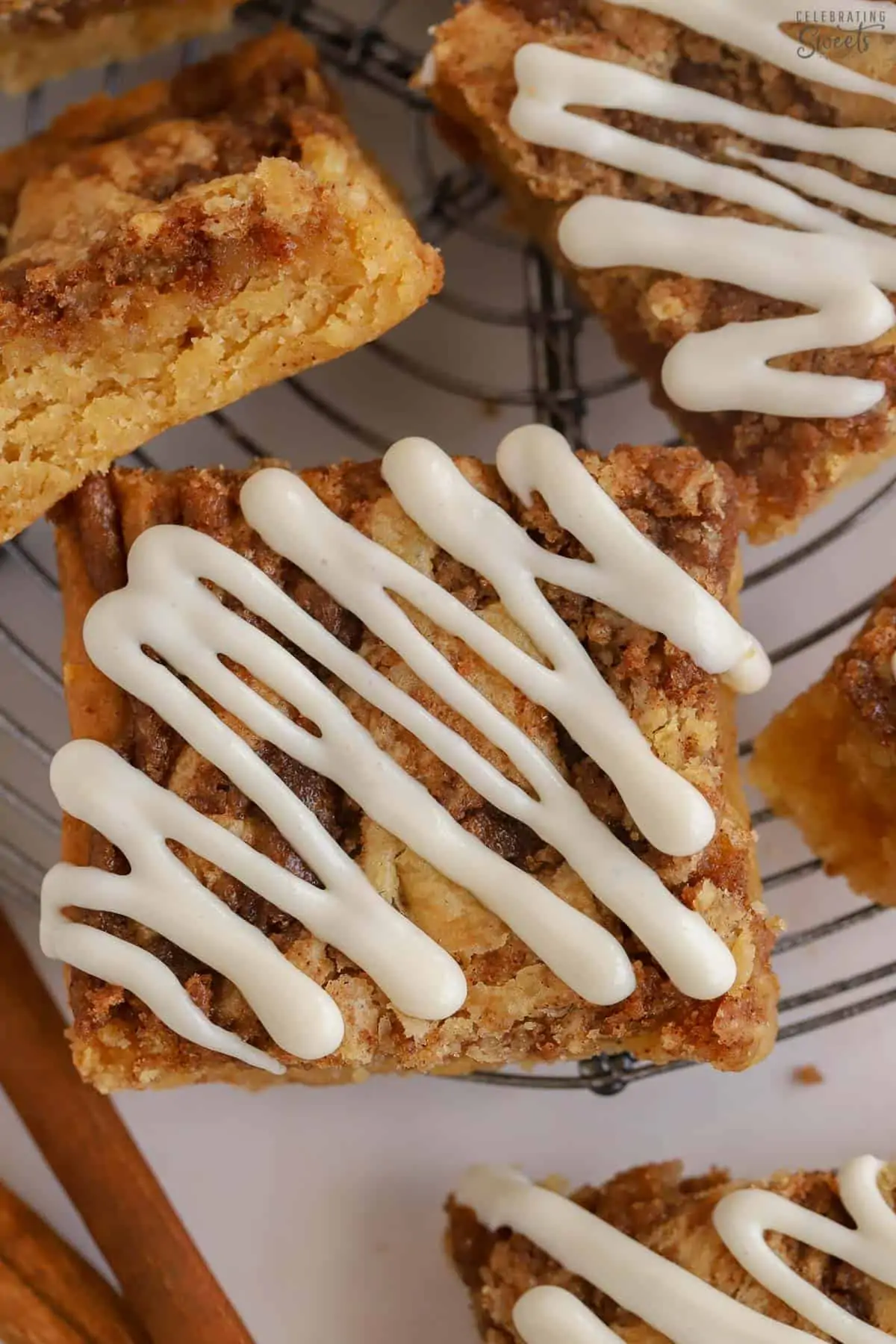 Cinnamon roll blondies drizzled with white icing on a wire rack.