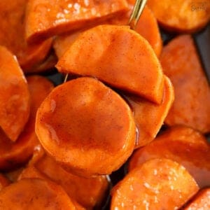 Closeup of candied sweet potatoes on a gold spoon.