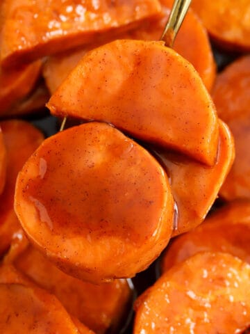 Closeup of candied sweet potatoes on a gold spoon.