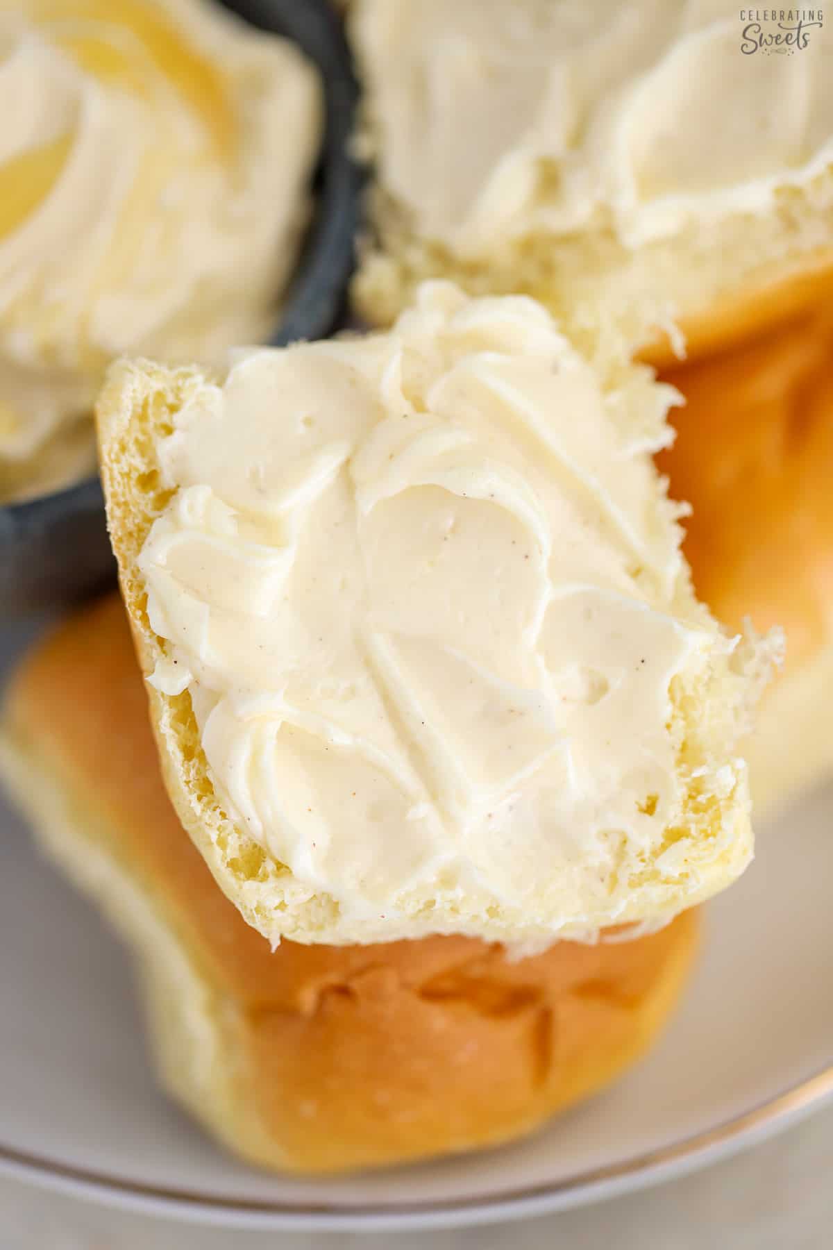 Closeup of a dinner roll topped with honey butter.
