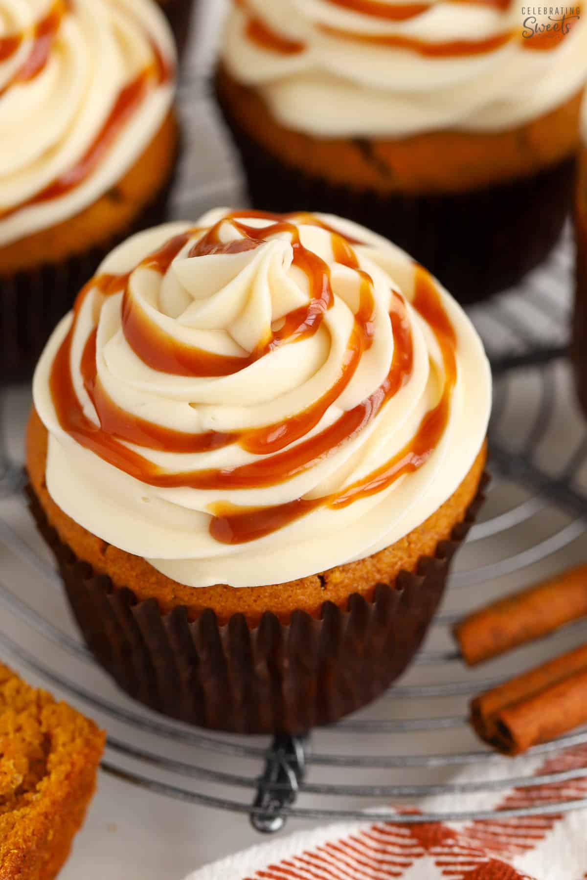 Closeup of pumpkin cupcake on a wire rack topped with caramel sauce.
