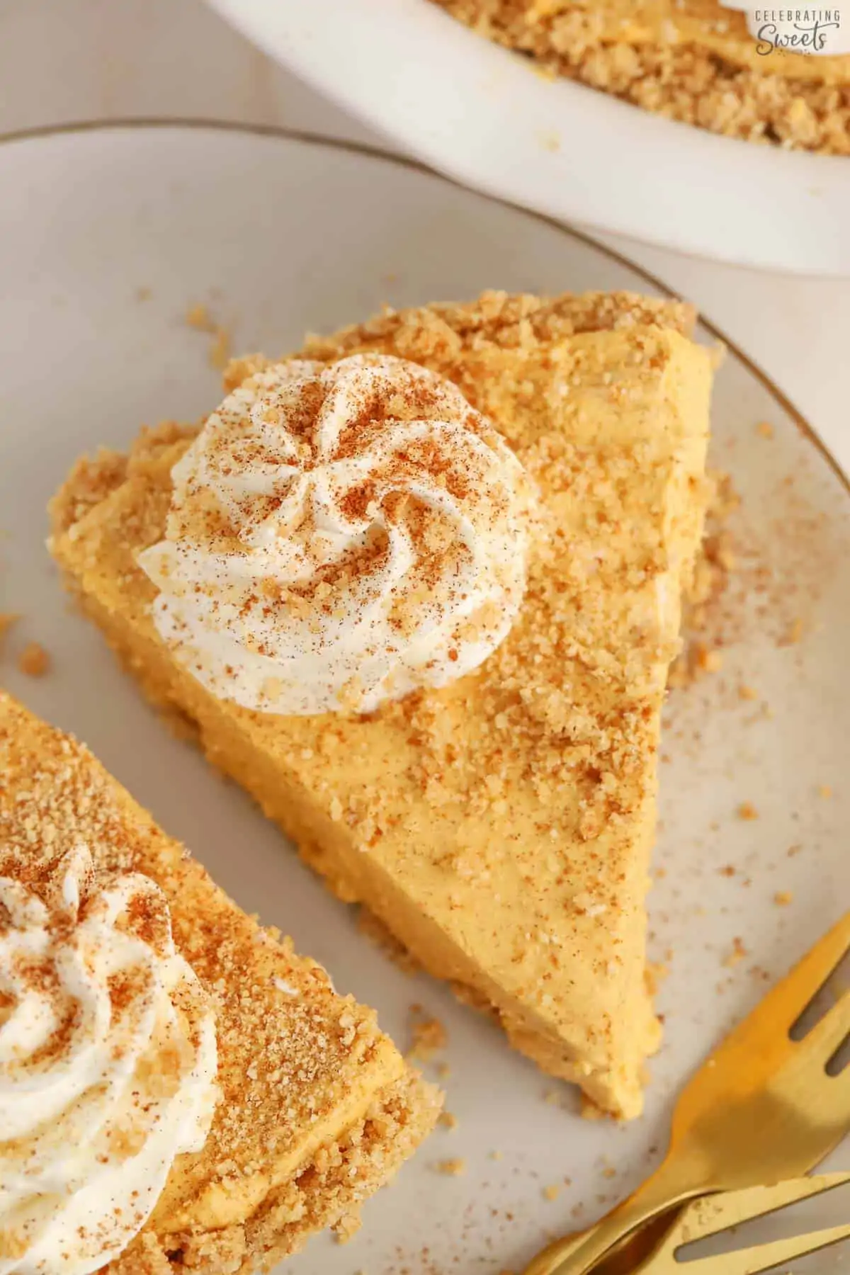 Slice of pumpkin pie cheesecake on a grey plate with a gold fork.