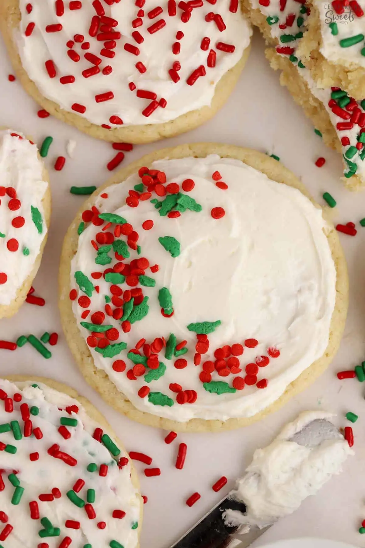 Sugar cookies topped with white frosting and red and green sprinkles.