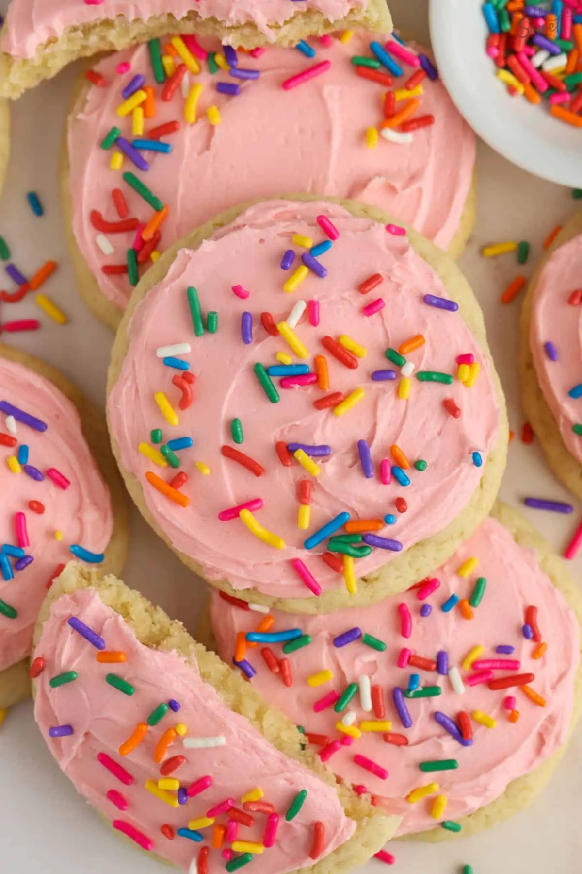Sugar cookies topped with pink frosting and colored sprinkles.