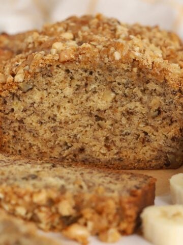 Loaf of banana nut bread cut open on a piece of parchment paper.