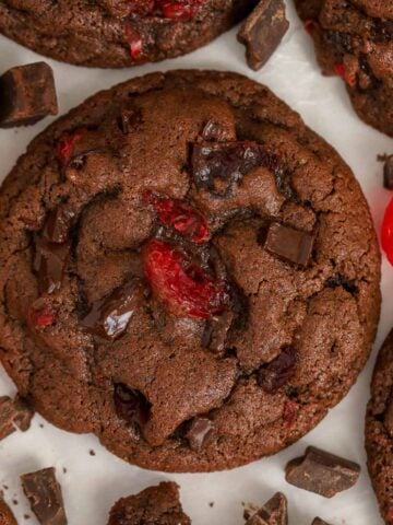 Closeup of chocolate cherry cookies on parchment paper.