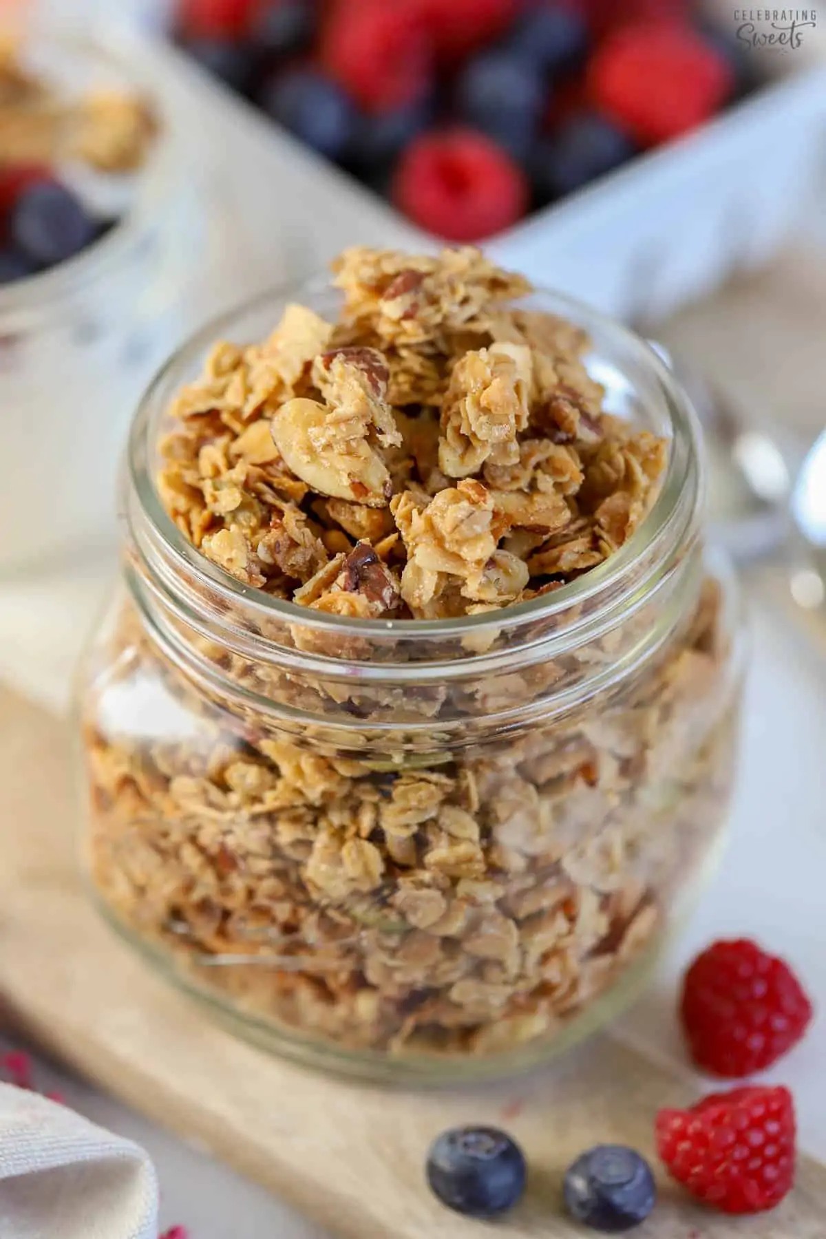 Granola in a glass jar on a wooden board.