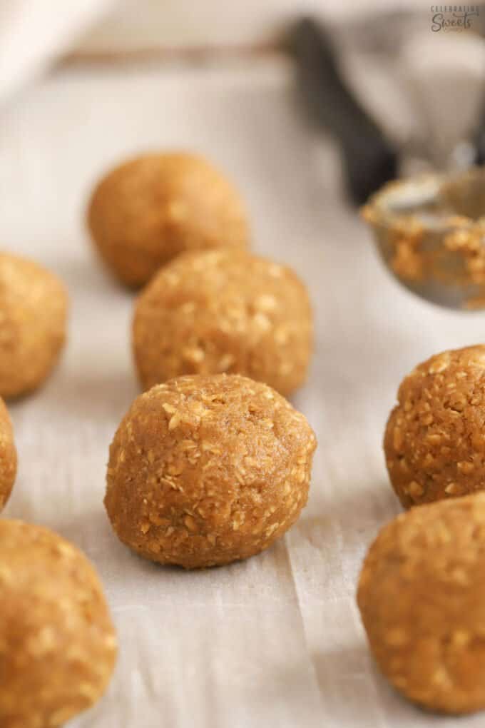 Oatmeal cookie dough balls on a parchment lined baking sheet.