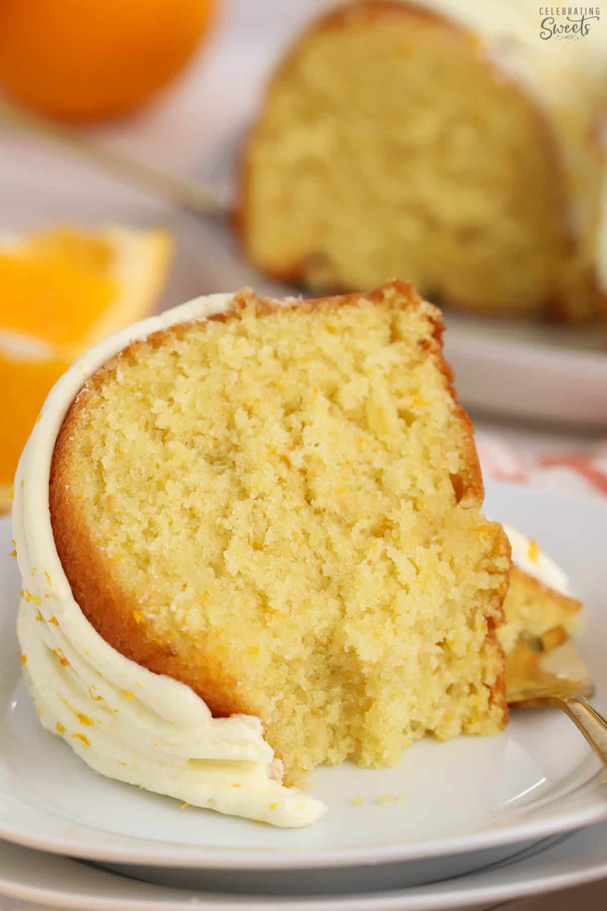 Slice of orange bundt cake on a white plate with a gold fork.