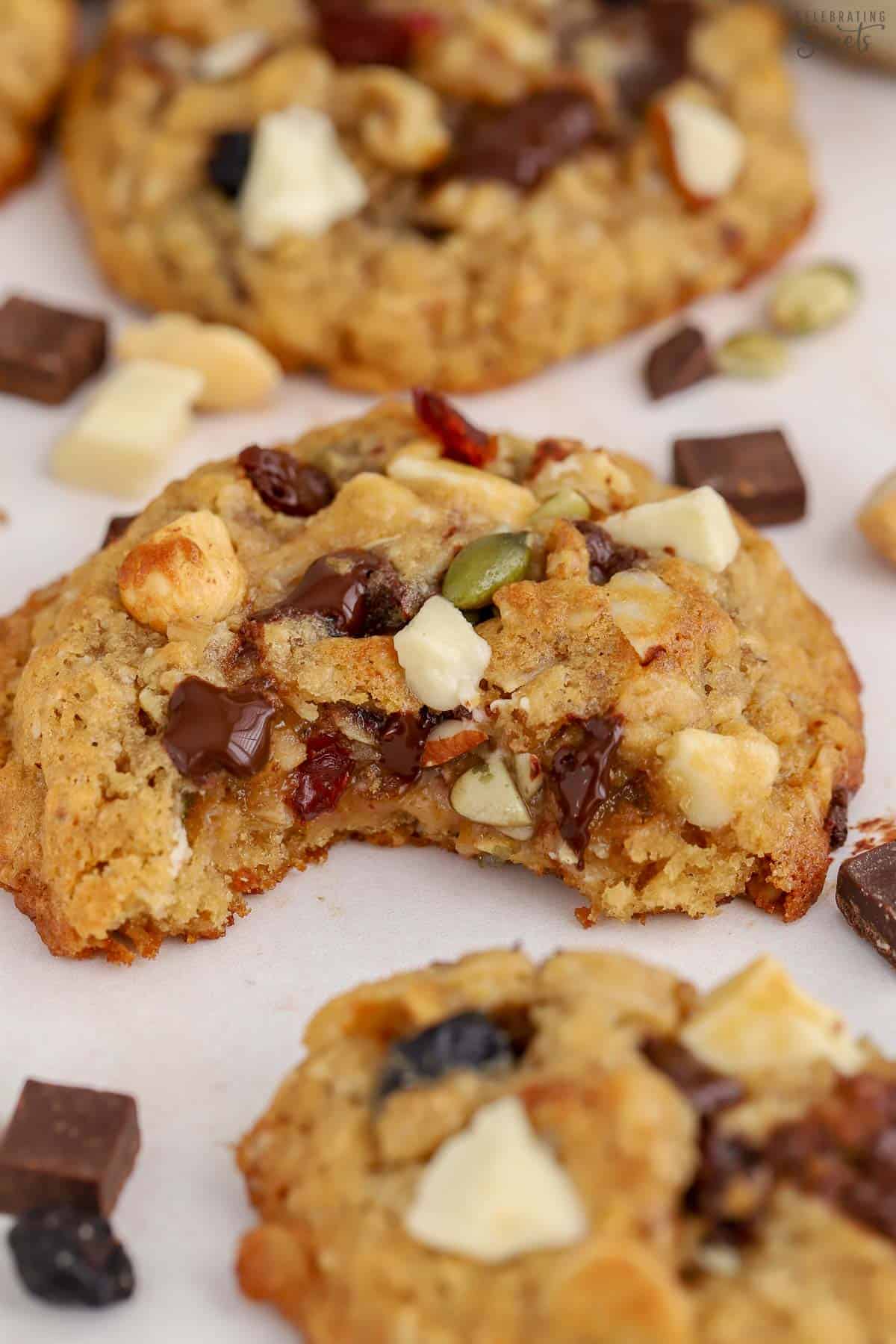 Trail mix cookie on a white board with a bite taken out of it.