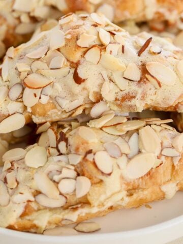 Stack of almond croissants on a white plate.