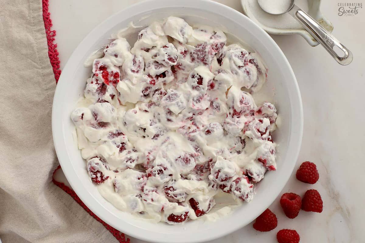 Raspberries and whipped cream in a white baking dish.