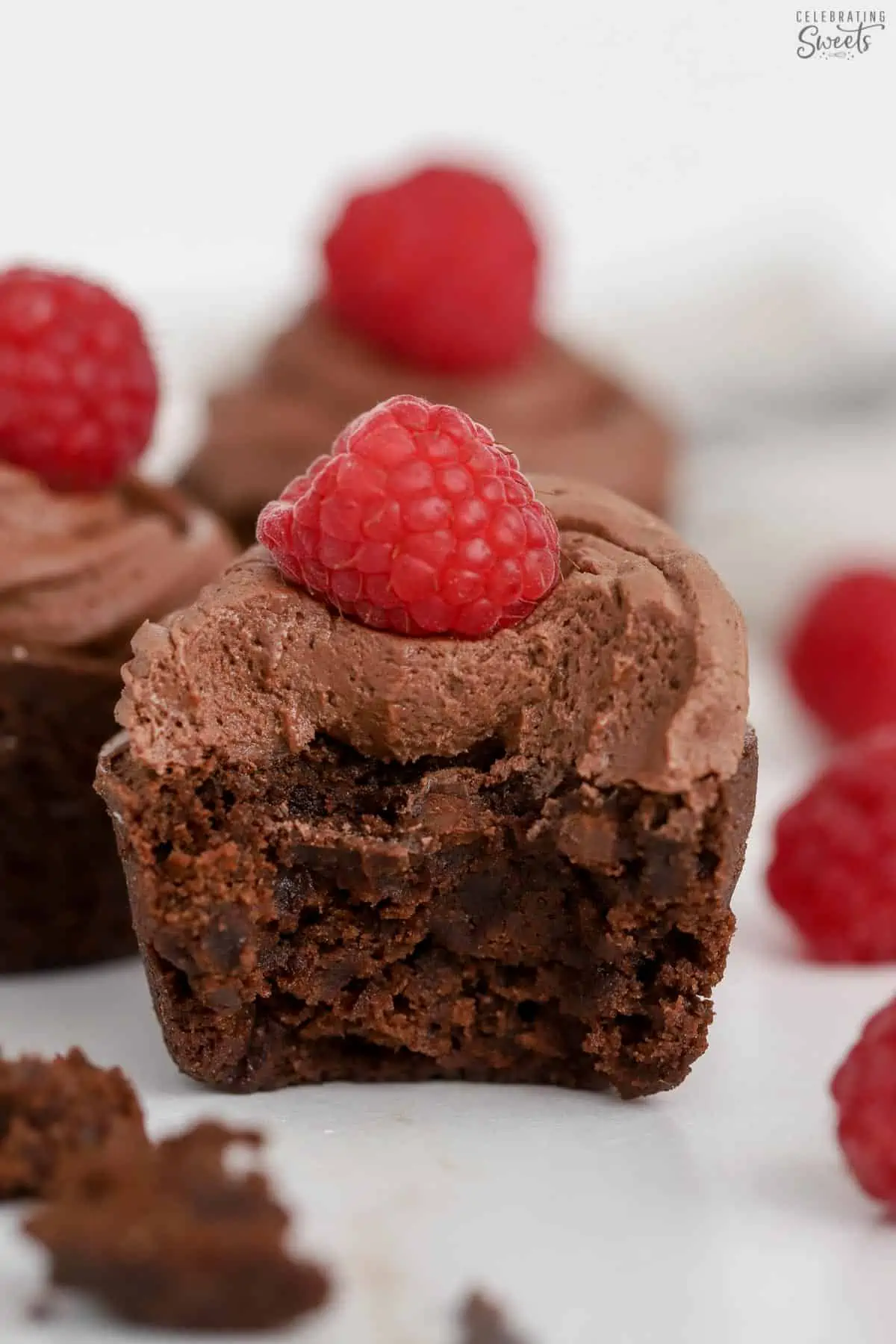 Half of a brownie bite topped with chocolate frosting and a raspberry.