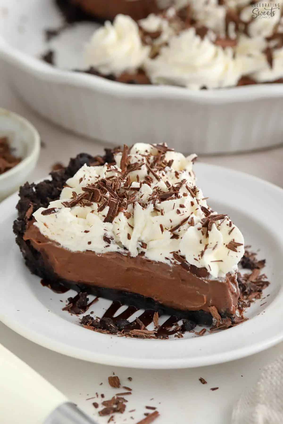 Slice of chocolate pie on a white plate topped with chocolate shavings.