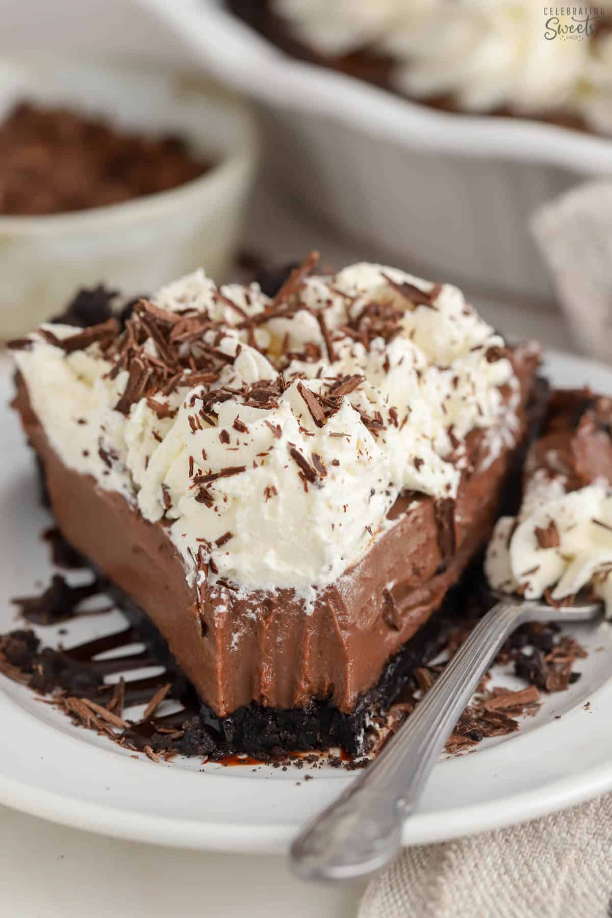 Slice of chocolate pie on a white plate topped with chocolate shavings.