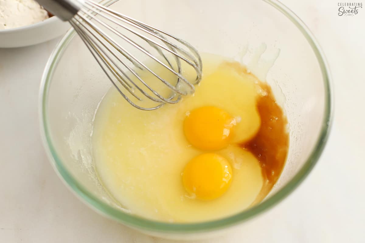 Eggs, sugar, butter, vanilla in a glass bowl.