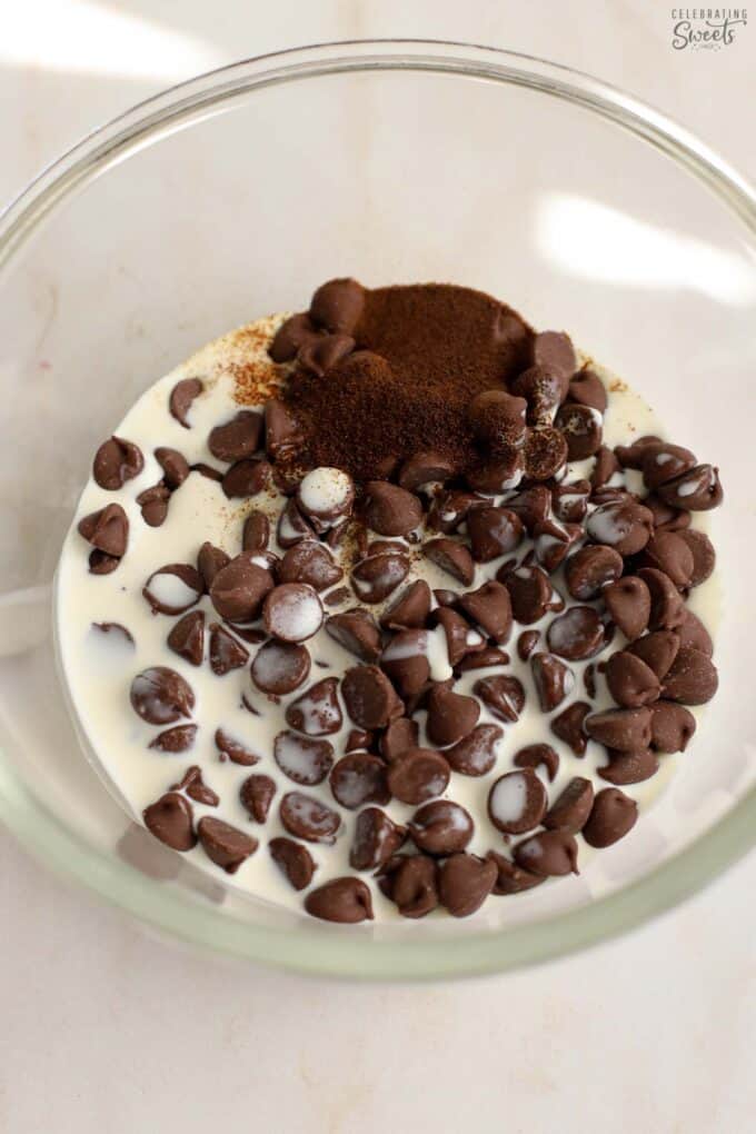 Chocolate chips, espresso powder, and cream in a glass bowl.