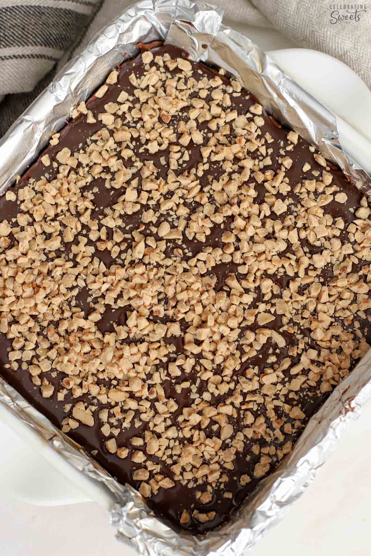 Brownies topped with toffee bits in a foil-lined square pan.