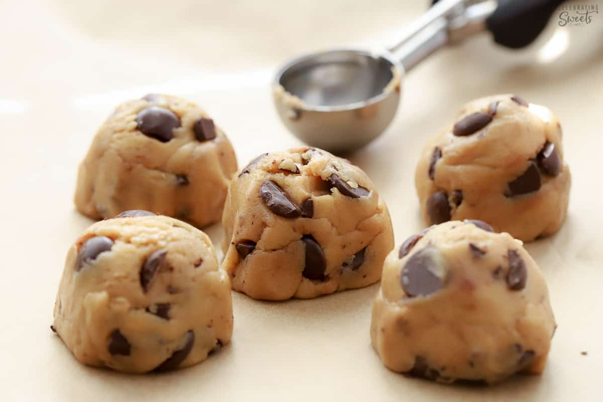 Scoops of chocolate chip cookie dough on parchment paper.