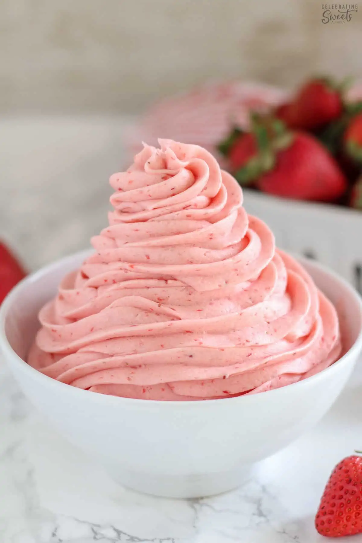 Strawberry buttercream frosting swirled in a white bowl.