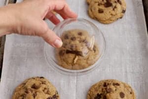 Glass bowl over a chocolate chip cookie on a baking sheet,
