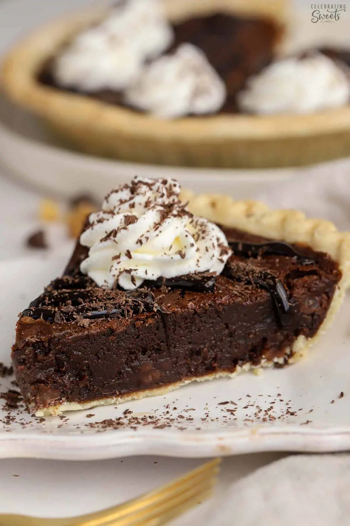 Slice of brownie pie topped with whipped cream and chocolate sauce.