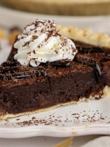 Slice of brownie pie topped with whipped cream and chocolate sauce.