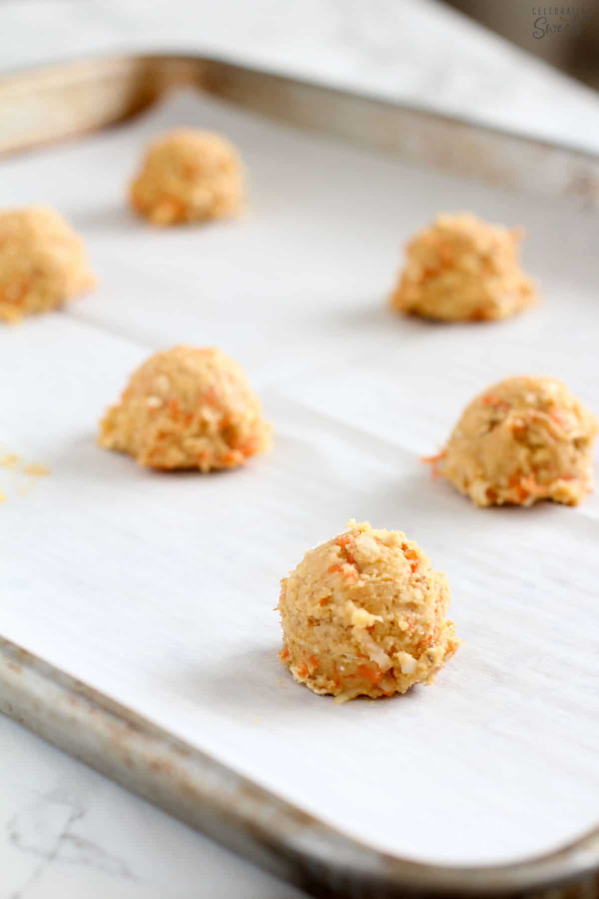 Scoops of carrot cake cookie dough on a baking sheet.