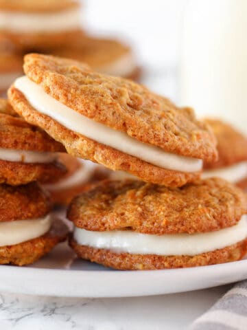 Stack of carrot cake cookies on a white plate.