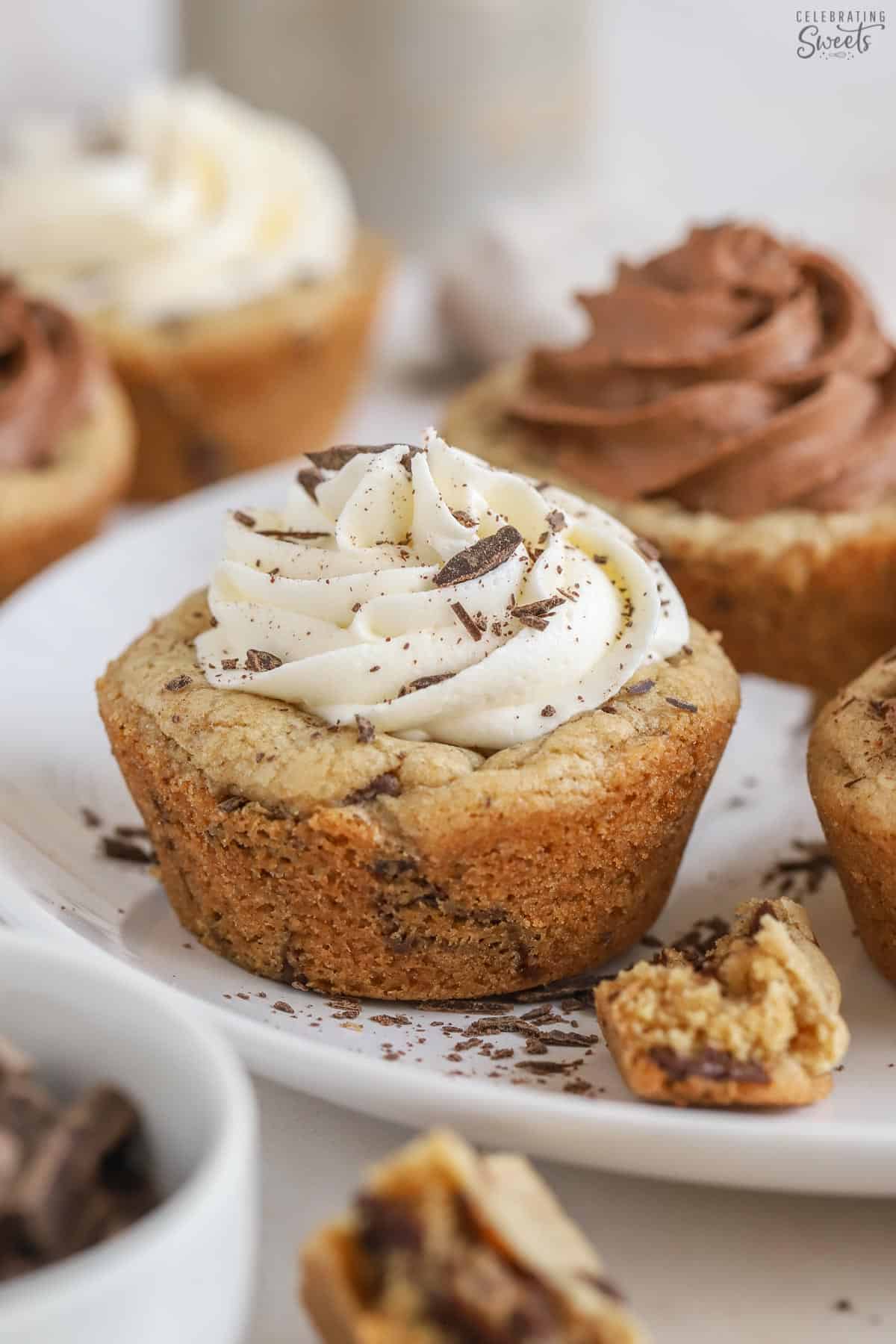 Cookie cups on a white plate topped with vanilla and chocolate frosting.
