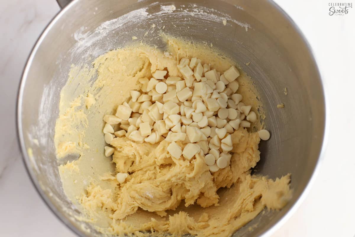 Lemon cookie dough in a mixing bowl with white chocolate chips.