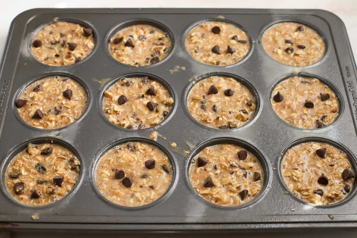 Baked oatmeal batter in muffin cups topped with chocolate chips.