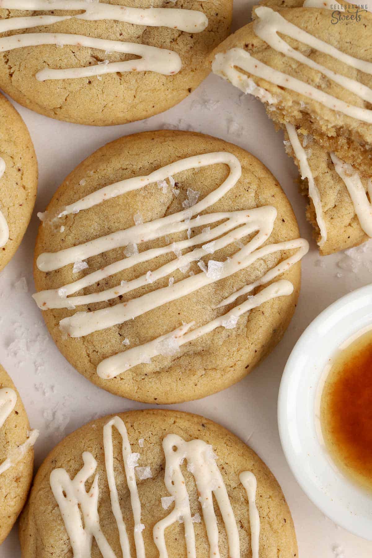 Closeup of a brown butter cookie drizzled with icing and topped with flaky sea salt.