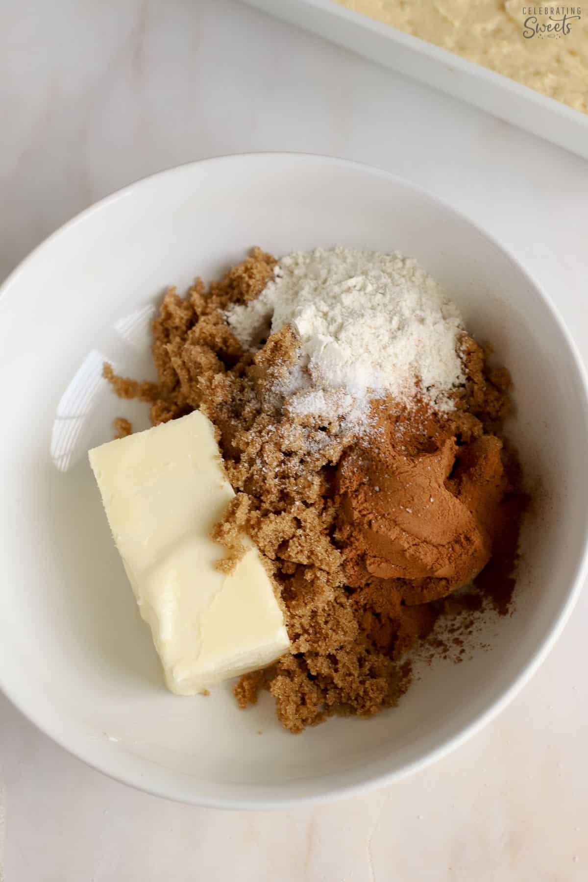 Butter, brown sugar, flour, and cinnamon in a white bowl.