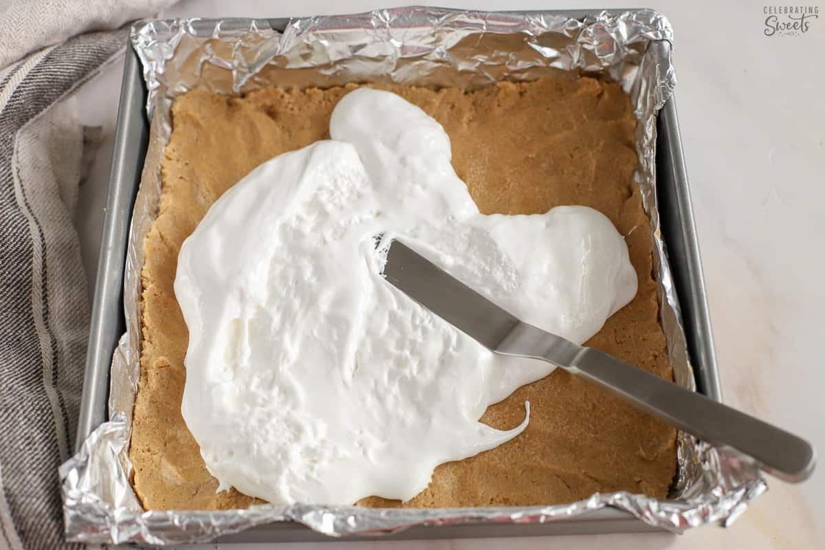 Marshmallow creme on top of cookie dough in a square pan.