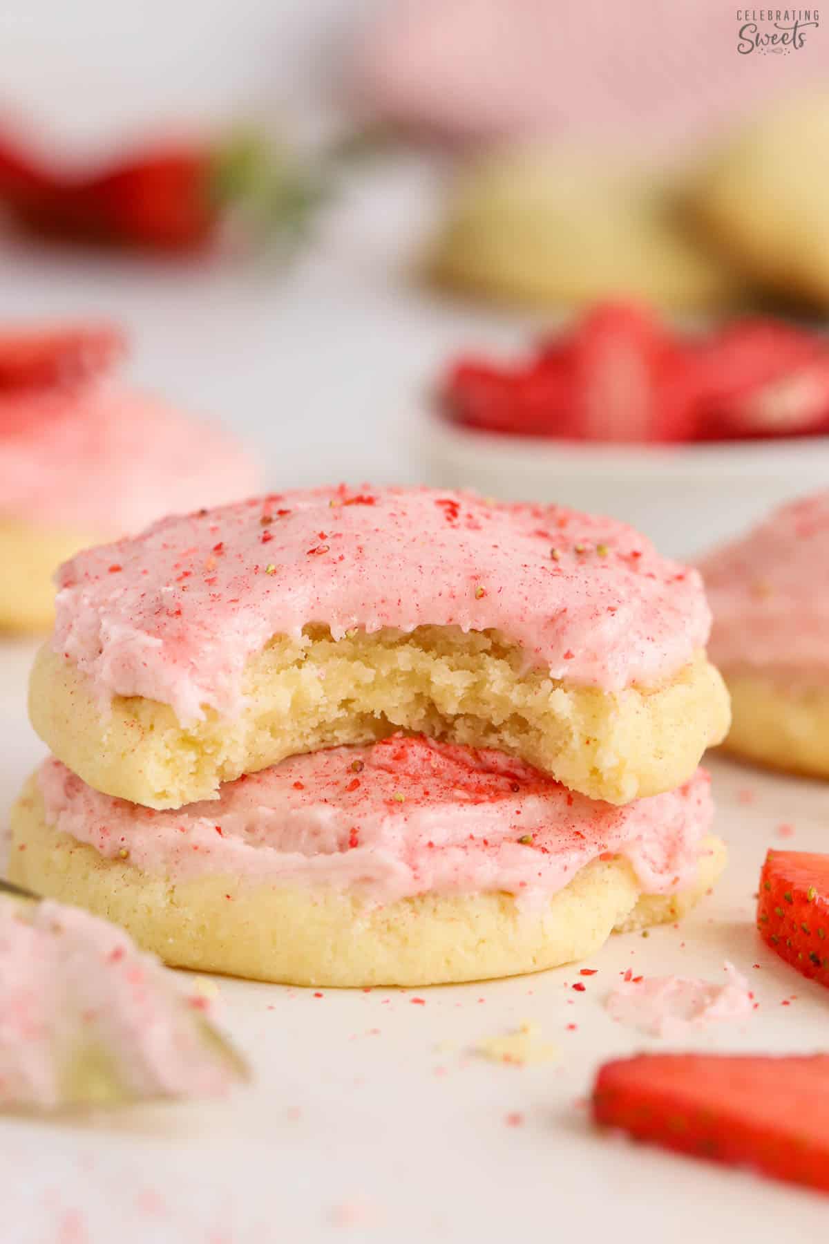 Stack of two sugar cookies topped with pink strawberry frosting.
