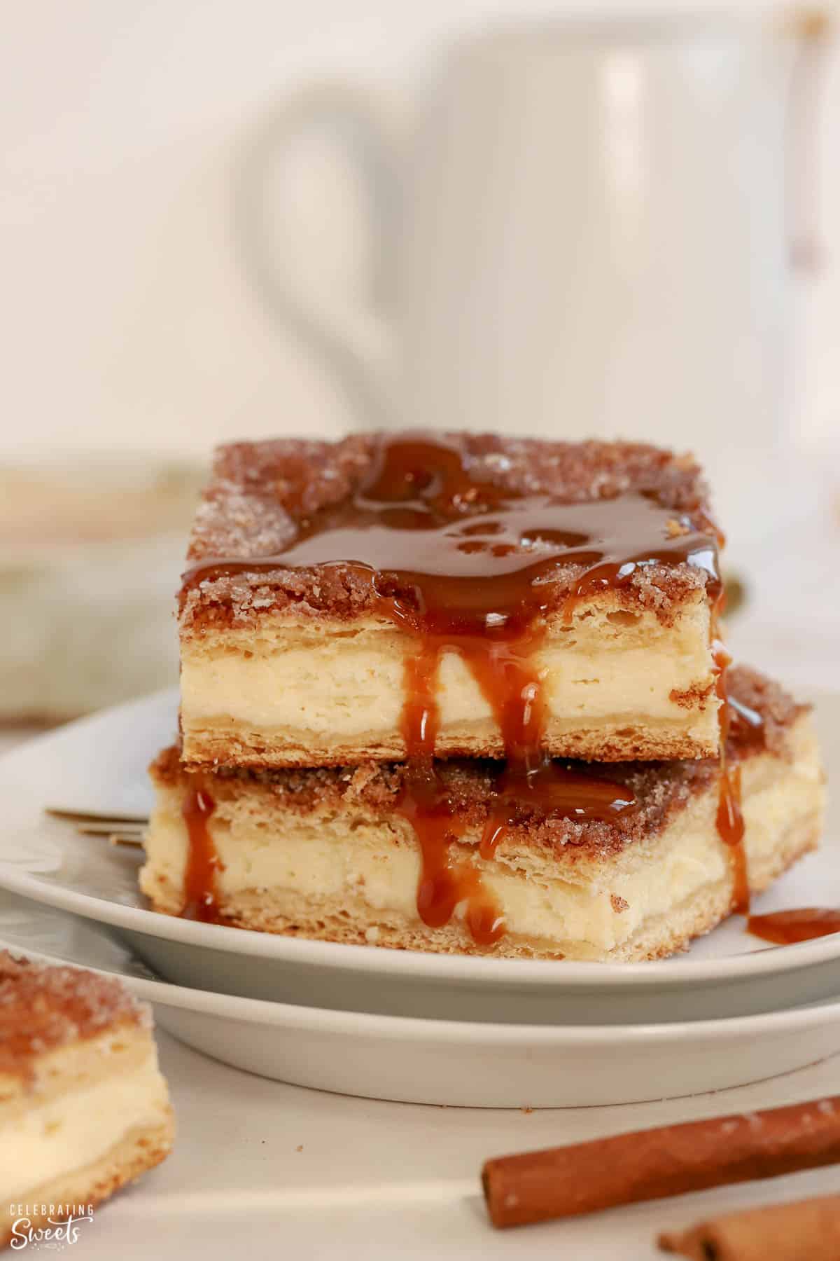 Stack of churro cheesecake bars topped with caramel sauce.