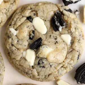 Closeup of a cookie topped with crushed oreos and white chocolate.