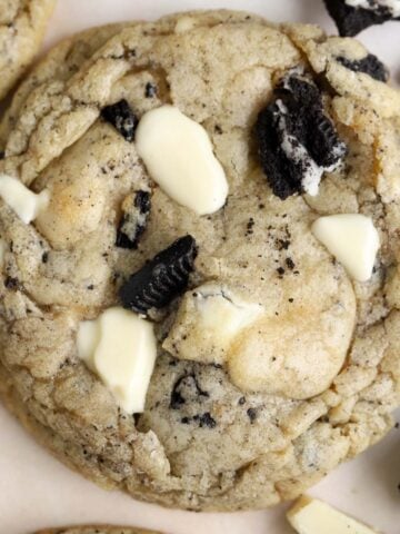 Closeup of a cookie topped with crushed oreos and white chocolate.