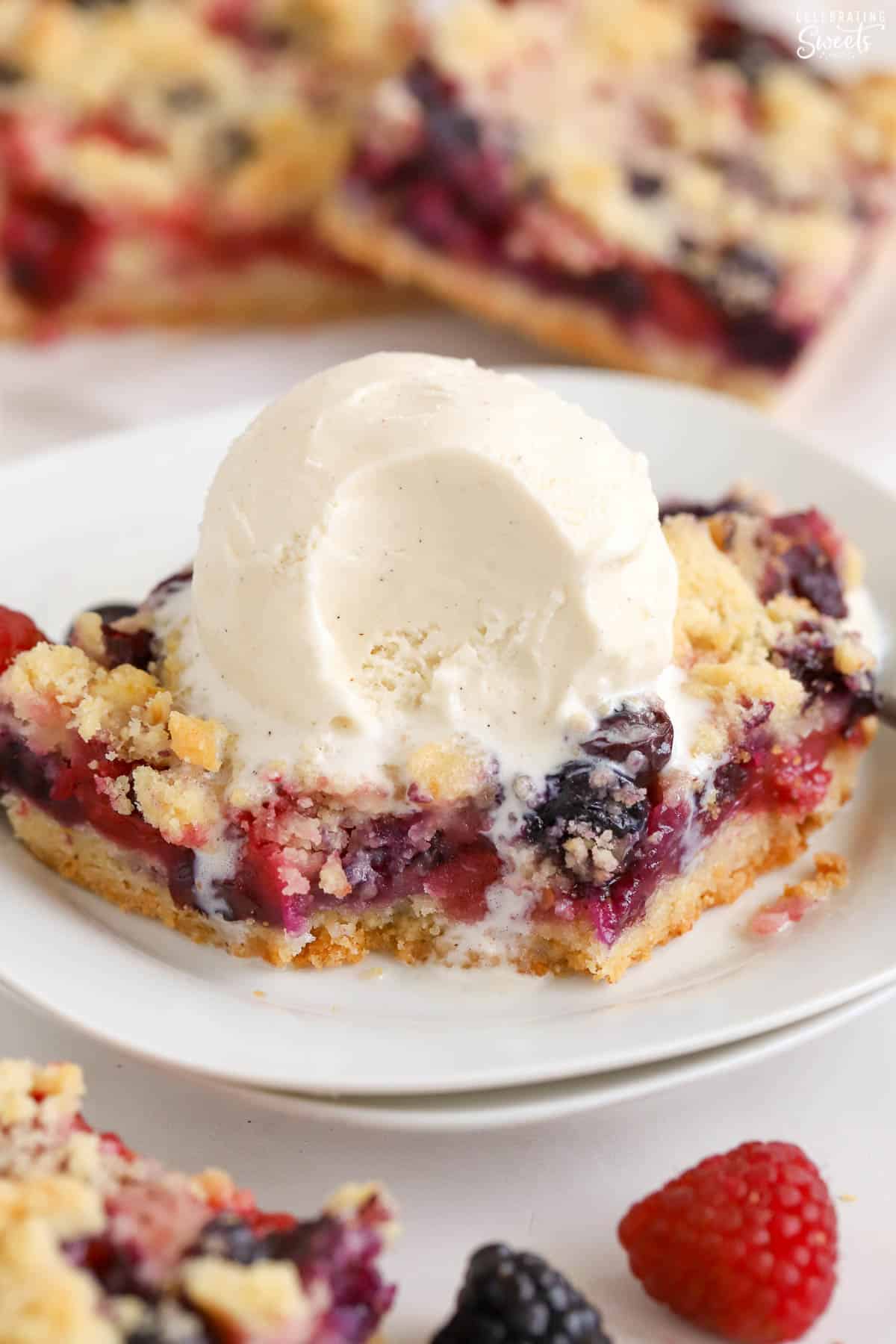 Berry crumble bar on a white plate with a scoop of ice cream.